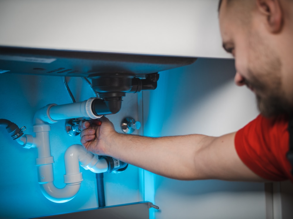 Plumber repairing a pipe inside an open wall